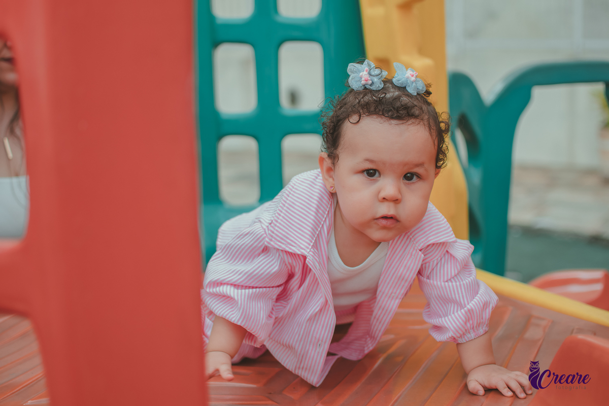 Uma bebê de 1 ano, brincando no parquinho do condomínio, durante sua festa de aniversário em casa.