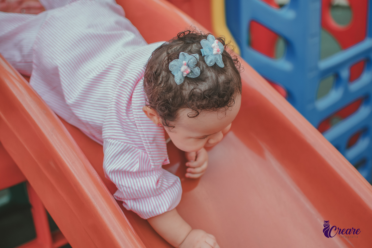 Uma bebê, descendo no escocrregador, durante festa de aniversário de 1 ano