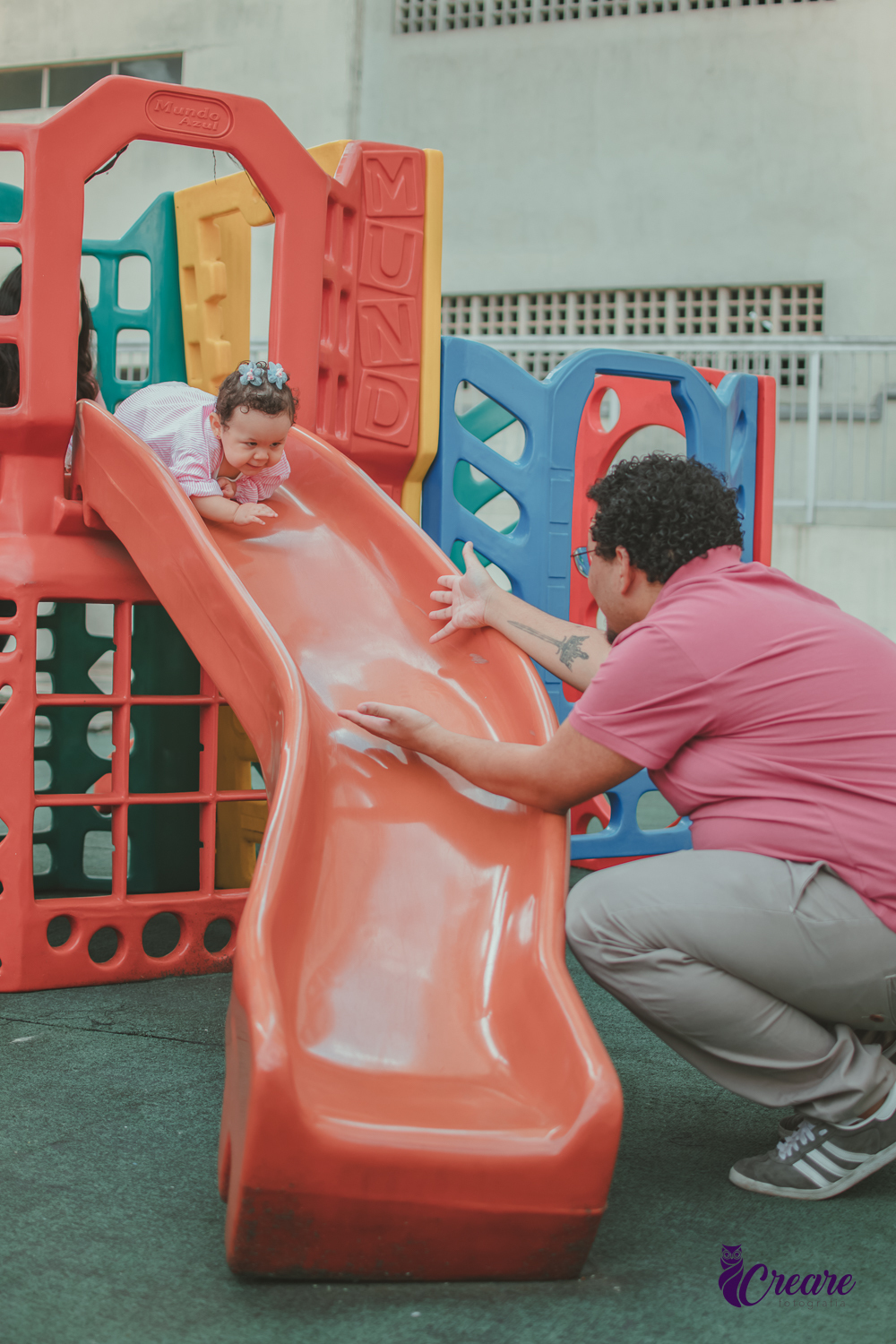 Uma bebê brincando com seu pai de descer no escorregador, durante sua festa de aniversário de 1 ano em casa.