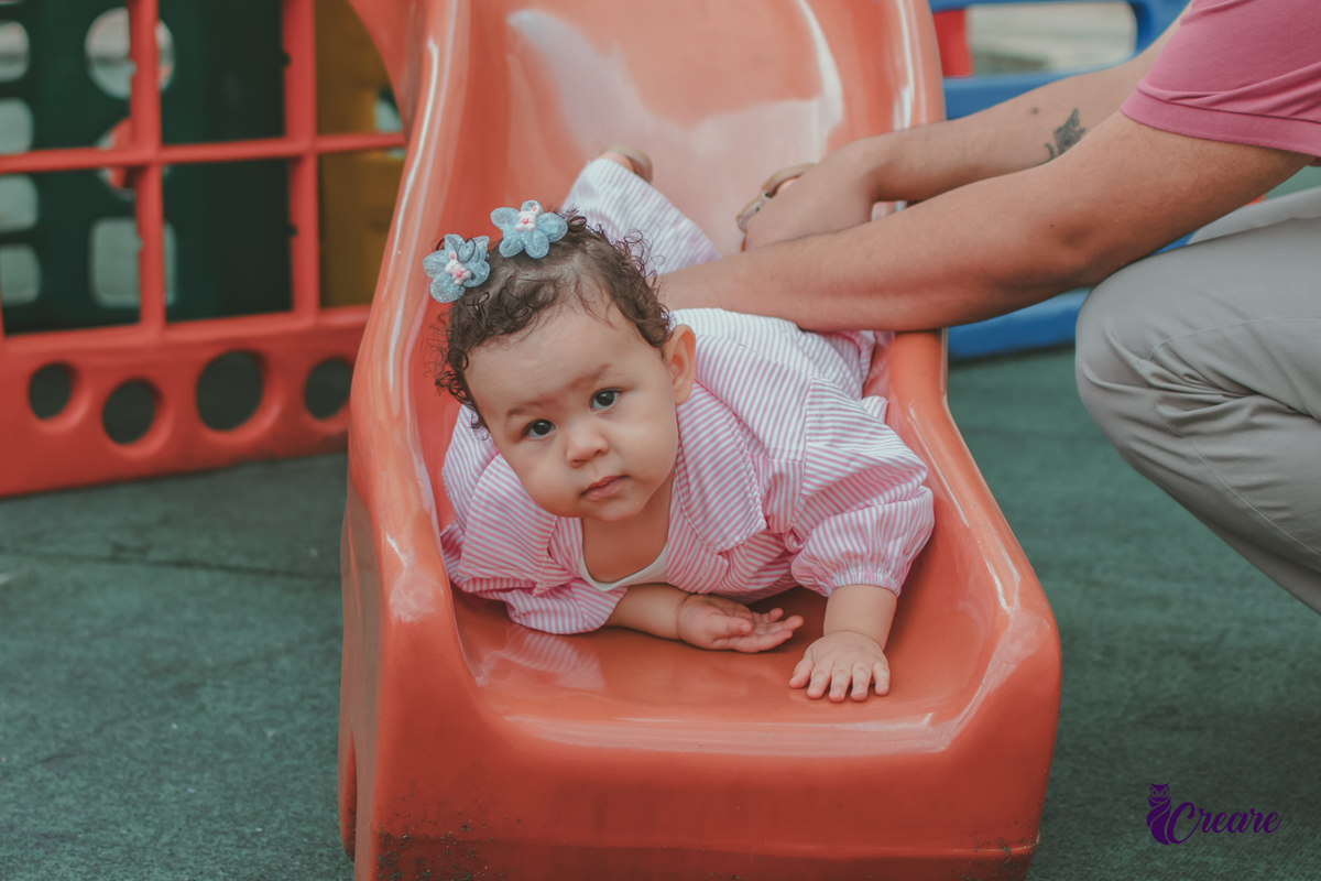 Uma bebê, descendo no escocrregador, durante festa de aniversário de 1 ano