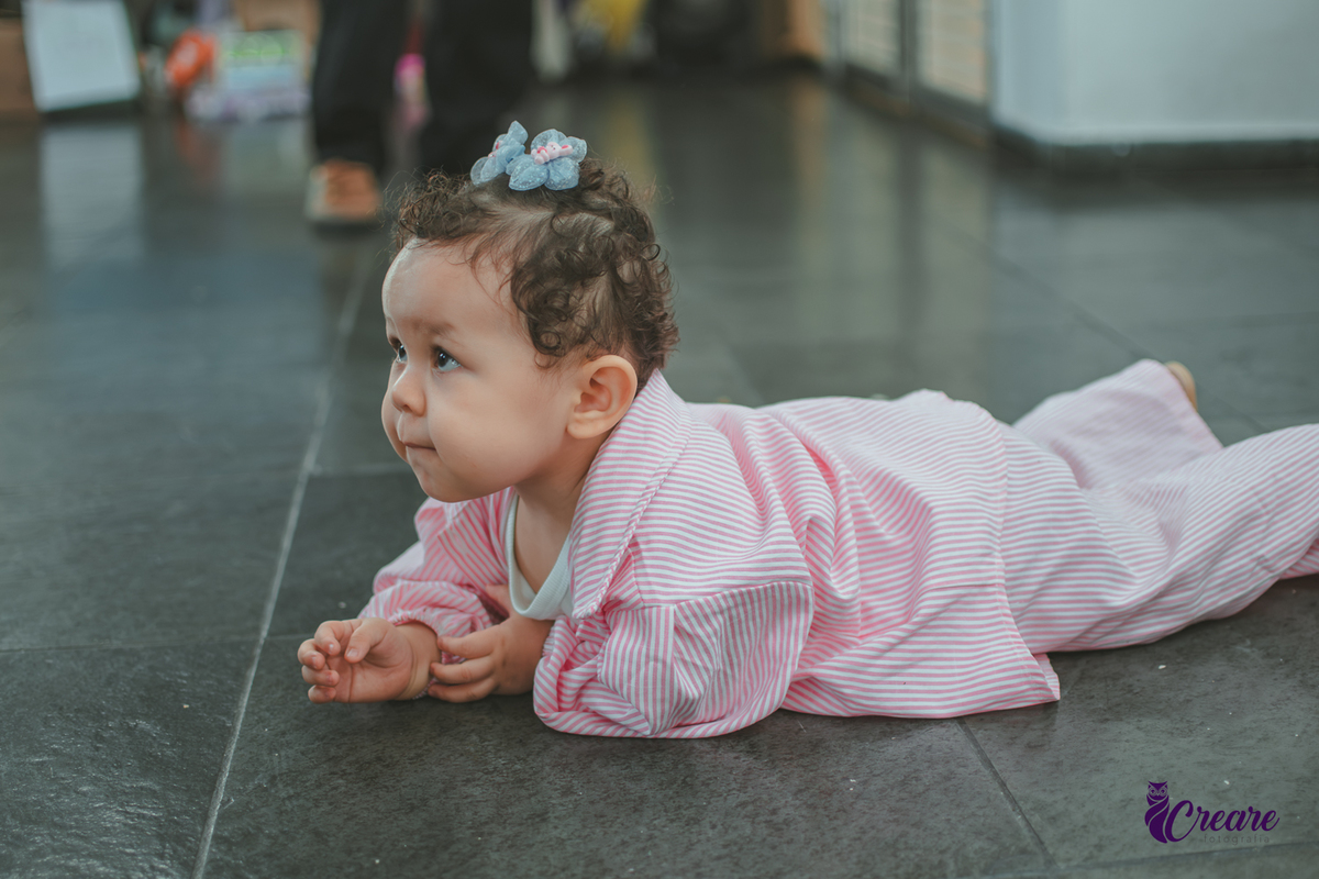 Uma bebê engatinhando no chão durante sua festa de aniversário de 1 ano.