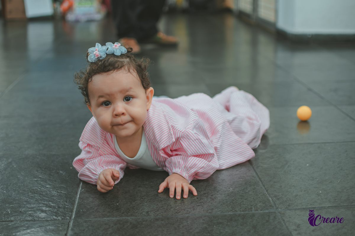 Uma bebê engatinhando no chão durante sua festa de aniversário de 1 ano.