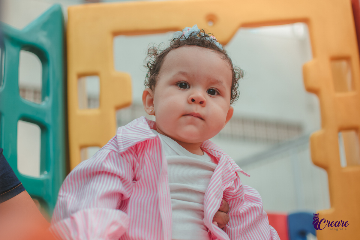 Uma bebê de 1 ano, brincando no parquinho do condomínio, durante sua festa de aniversário em casa.