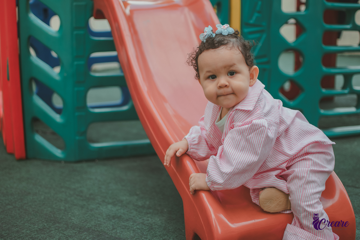 Uma bebê de 1 ano, brincando no parquinho do condomínio, durante sua festa de aniversário em casa.Uma bebê de 1 ano, brincando no parquinho do condomínio, durante sua festa de aniversário em casa.