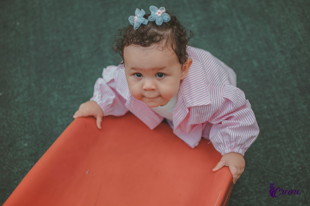 Uma bebê de 1 ano, brincando no parquinho do condomínio, durante sua festa de aniversário em casa.