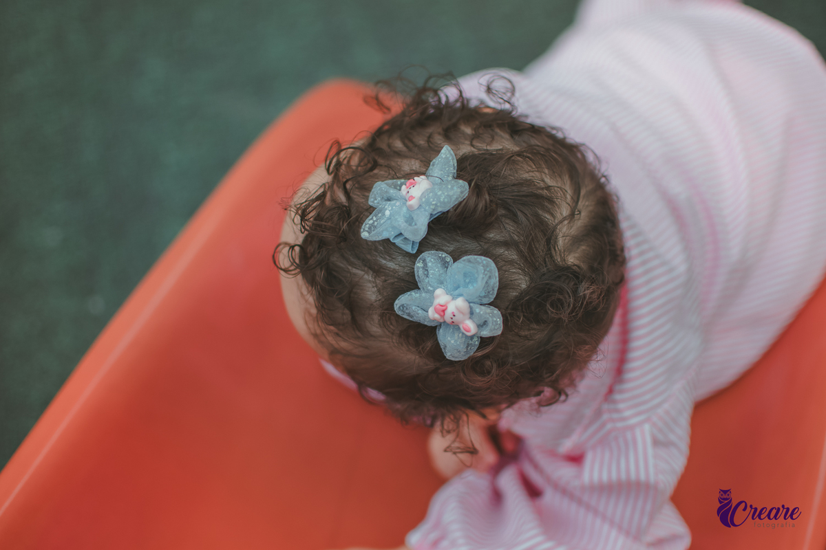 Uma bebê de 1 ano, brincando no parquinho do condomínio, durante sua festa de aniversário em casa.