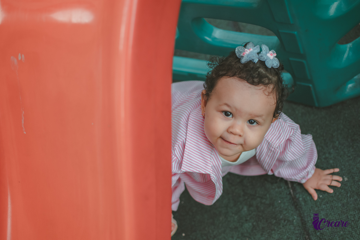 Uma bebê de 1 ano, brincando no parquinho do condomínio, durante sua festa de aniversário em casa.