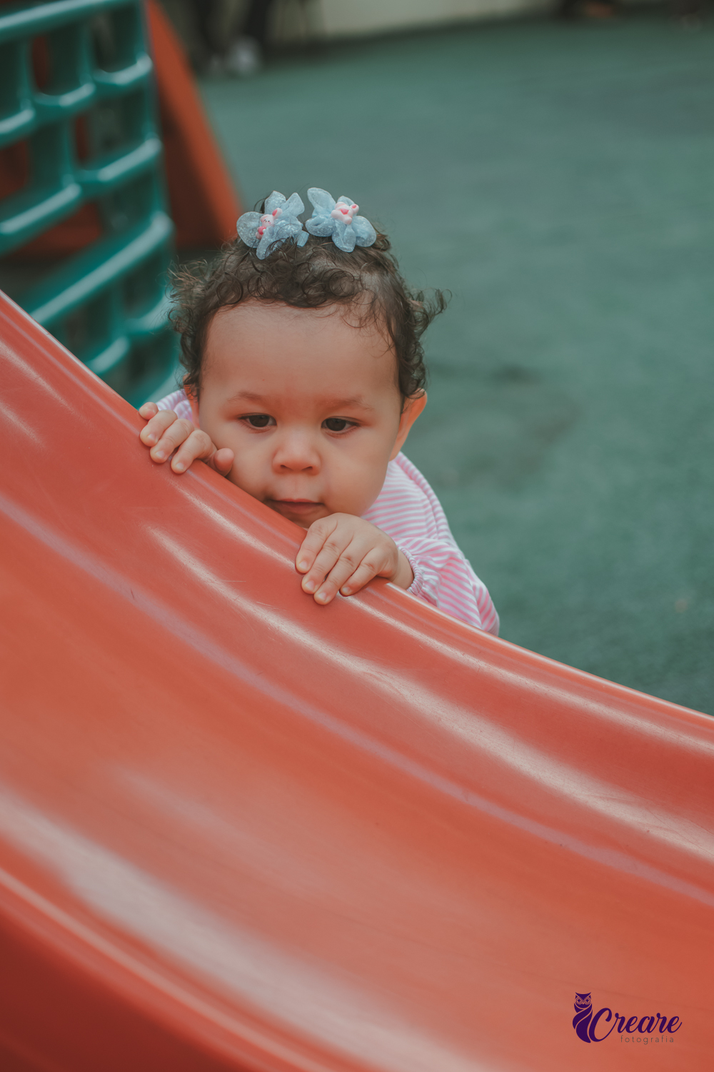 Uma bebê de 1 ano, brincando no parquinho do condomínio, durante sua festa de aniversário em casa.