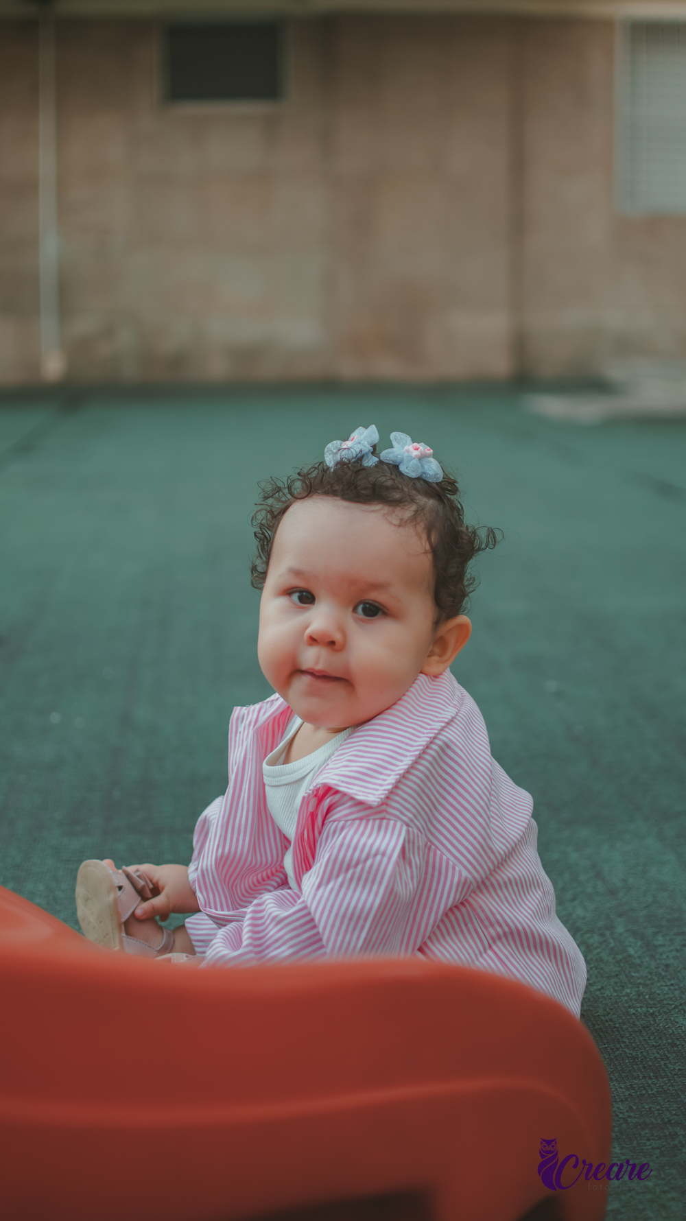 Uma bebê de 1 ano, brincando no parquinho do condomínio, durante sua festa de aniversário em casa.