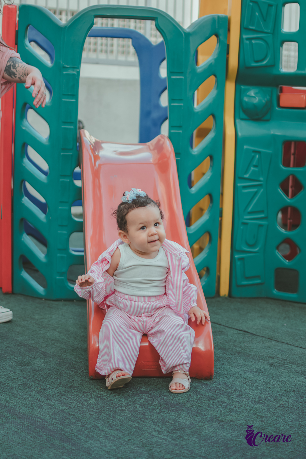 Uma bebê brincando no escorregador, durante sua festa de aniversário de 1 ano no salão do condomínio.