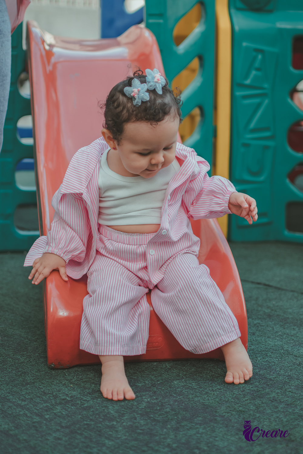 Uma bebê brincando no escorregador, durante sua festa de aniversário de 1 ano no salão do condomínio.