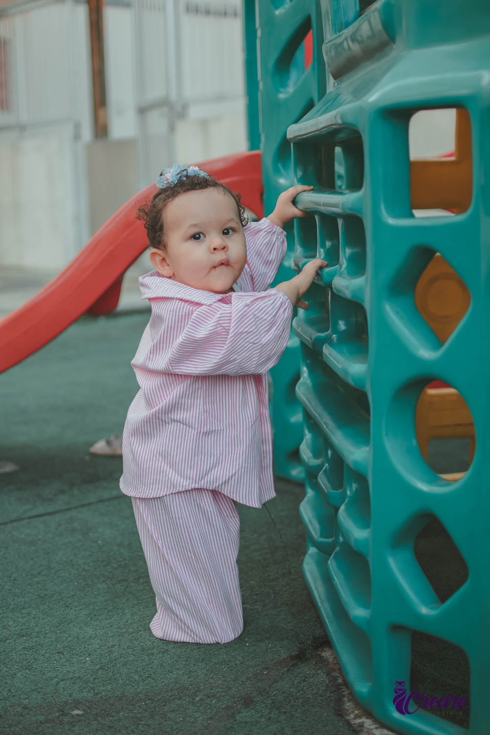 Uma bebê de 1 ano, brincando no parquinho do condomínio, durante sua festa de aniversário em casa.