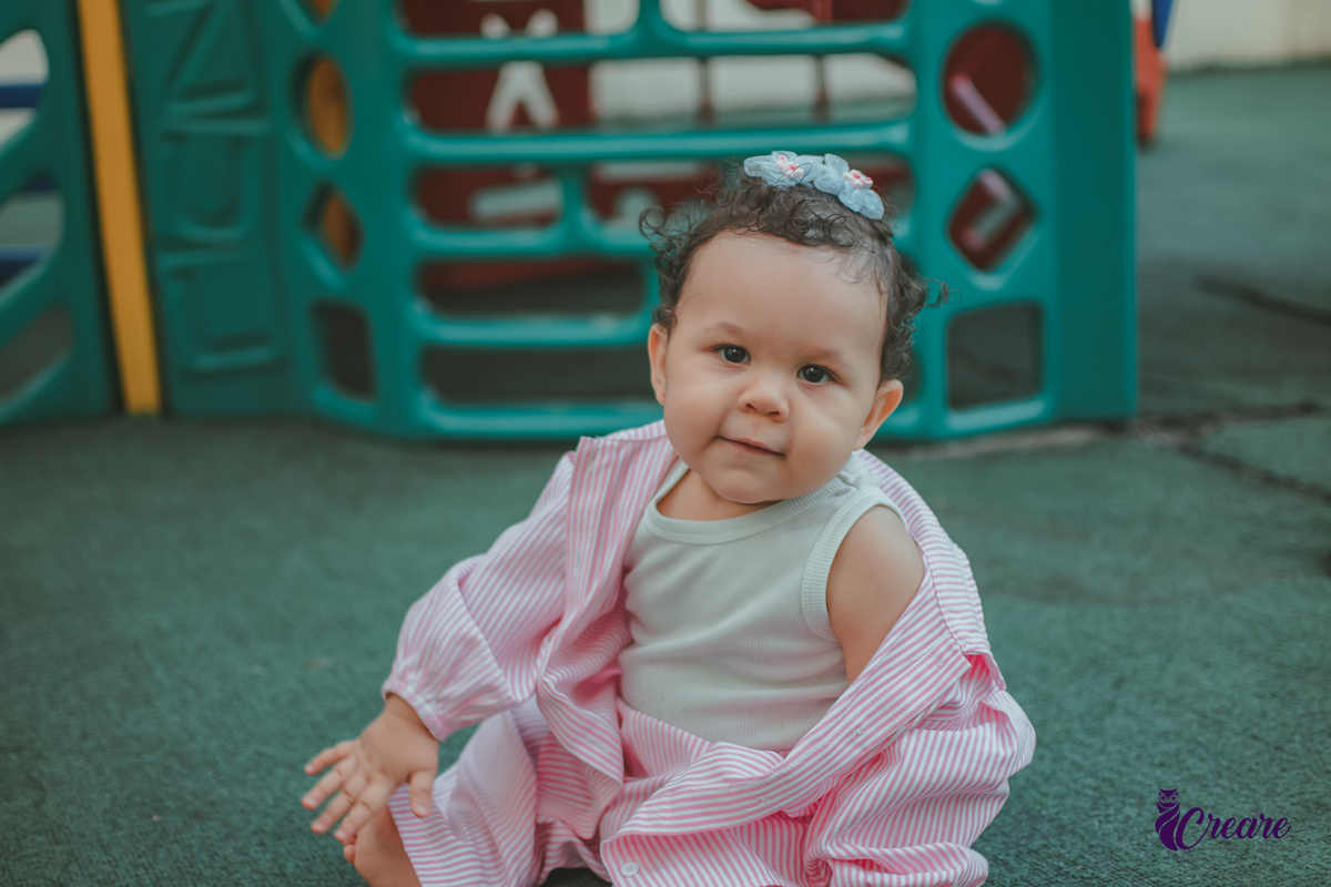 Uma bebê de 1 ano, brincando no parquinho do condomínio, durante sua festa de aniversário em casa.