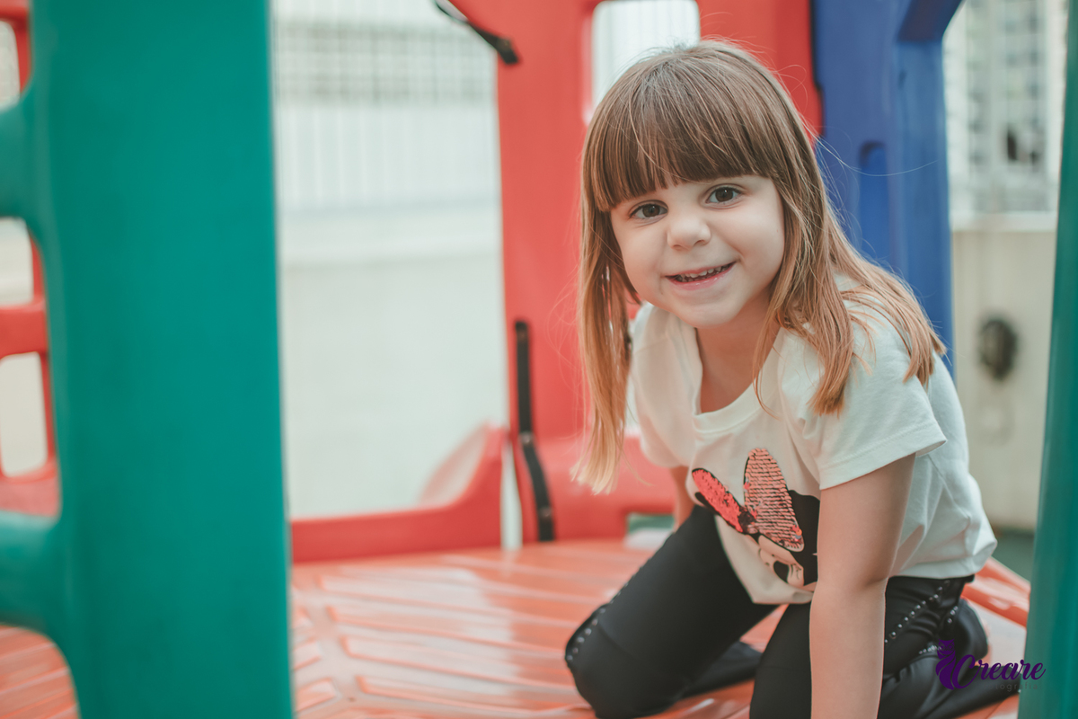 Uma menina brincando no parquinho do condomínio, durantes festa de aniversário em casa.