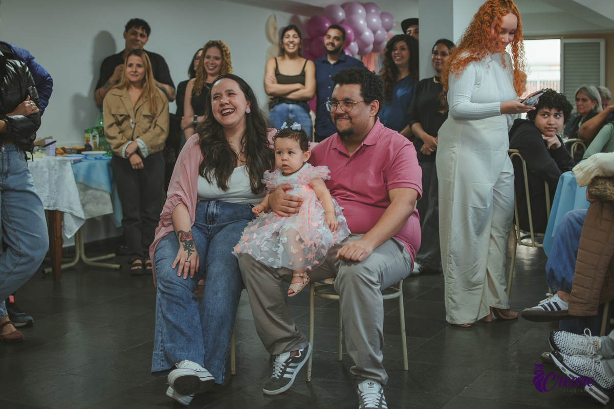 Um casal emocionado assistindo a restrospectiva, durante festa de aniversário de 1 ano em casa.