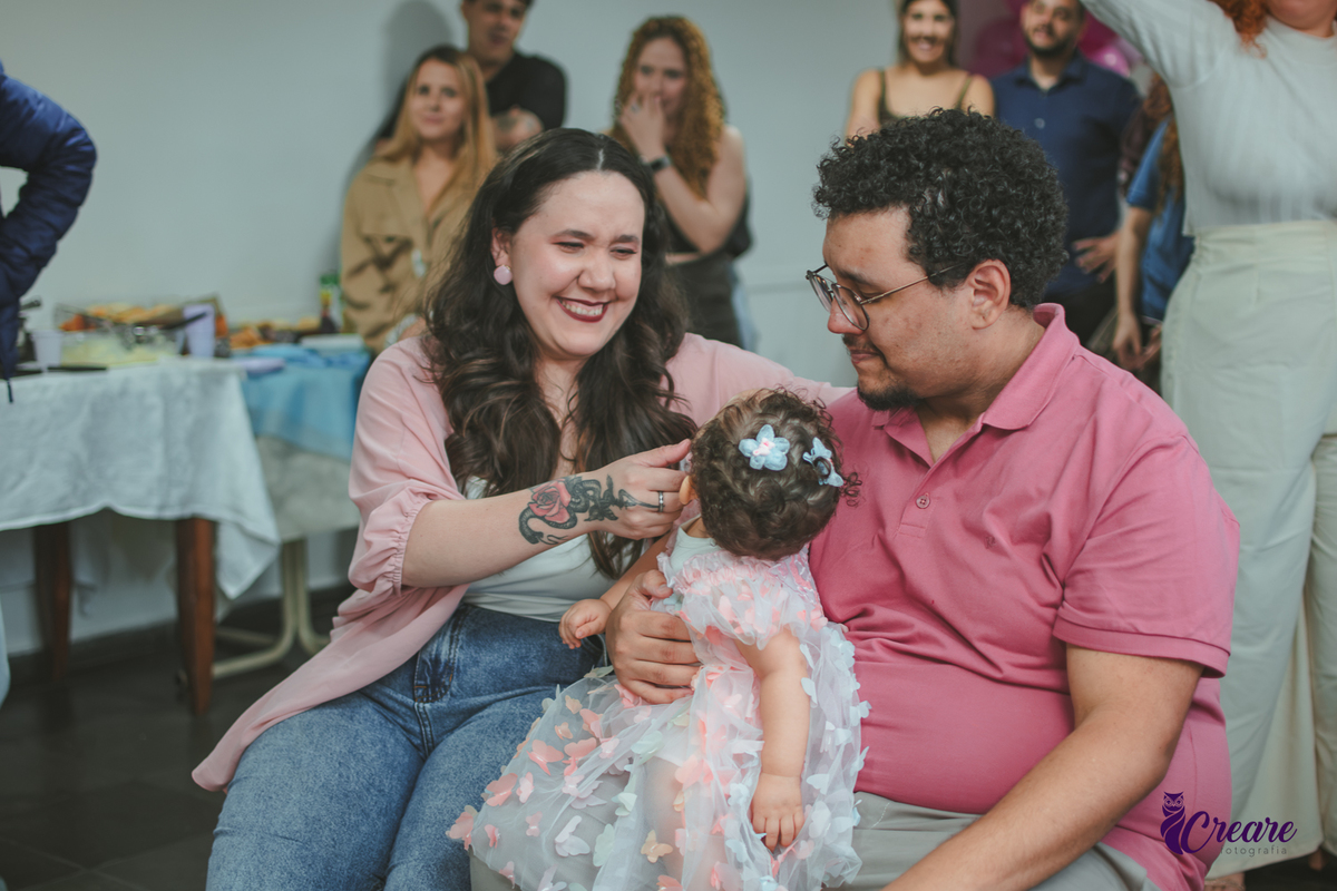 Um casal emocionado assistindo a restrospectiva, durante festa de aniversário de 1 ano em casa.