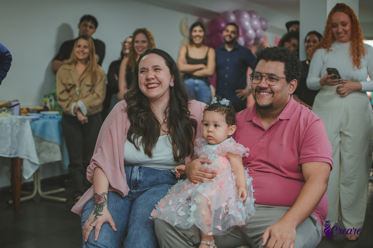 Um casal emocionado assistindo a restrospectiva, durante festa de aniversário de 1 ano em casa.