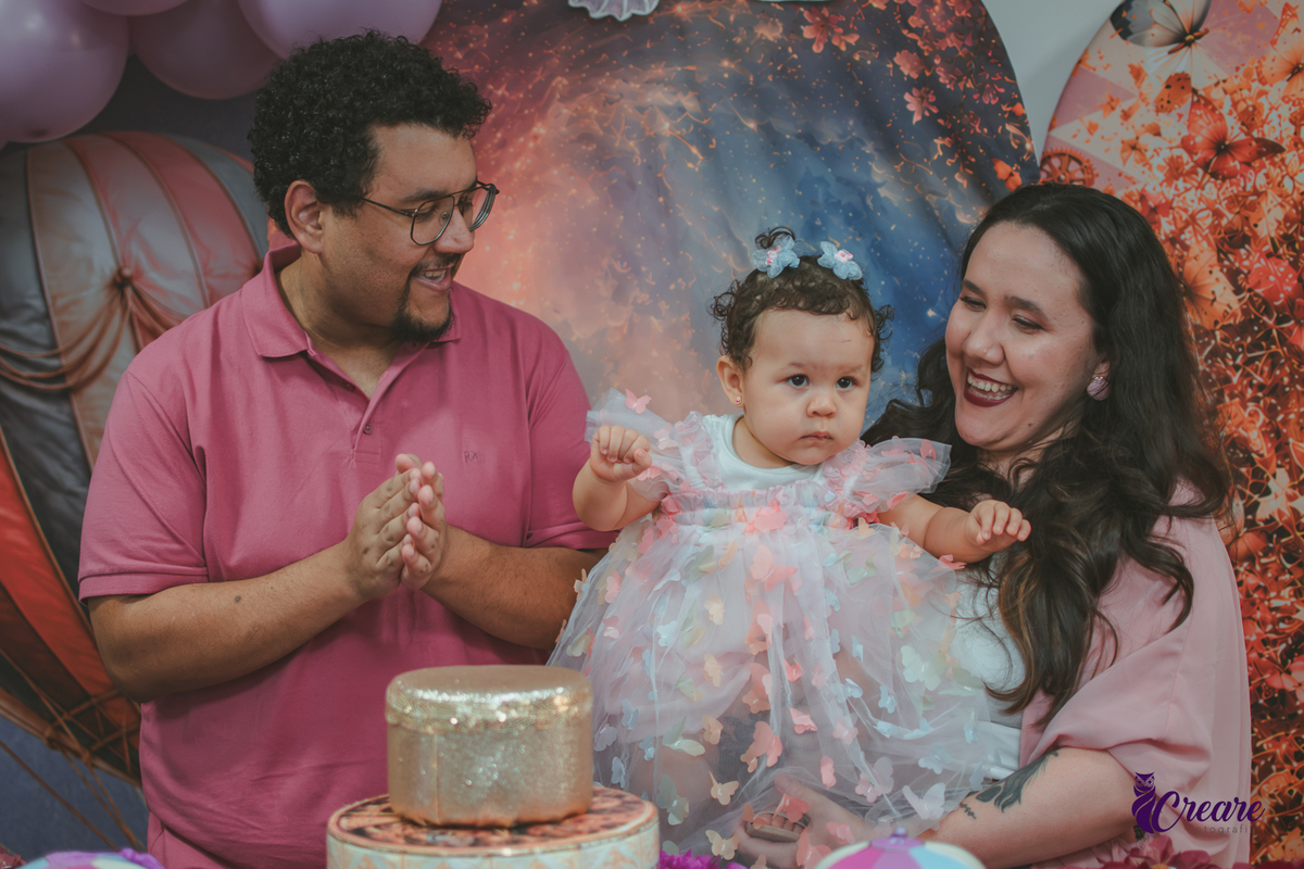 Um casal cantando parabéns, durante festa de aniversário de 1 ano em casa.