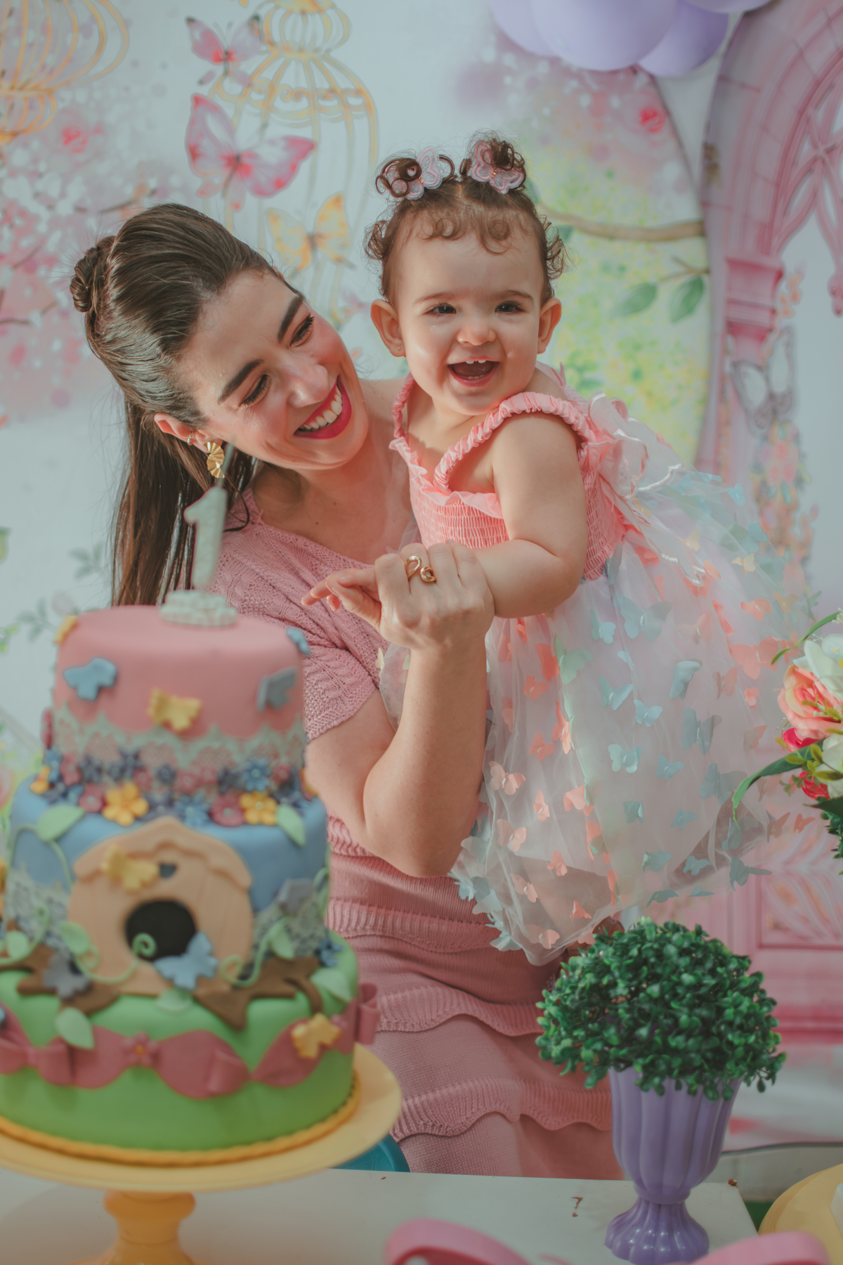 Uma mulher segurando um bebê que sorri, durante festa de aniversário de 1 ano em Santo André.