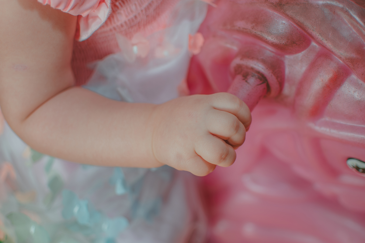 Detalhes da mão de uma bebê de uma nao segurando em um brinquedo, durante festa de aniversário de 1 ano.