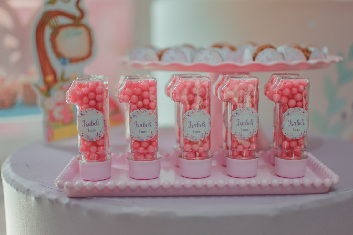 Potinhos com formato de número 1 e com bolinhas rosa dentro, como lembrancinha de aniversário de 1 ano.
