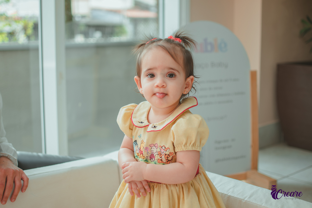 Uma bebê brincando na piscina de bolinhas brancas, durante sua festa de aniversário de 1 ano.