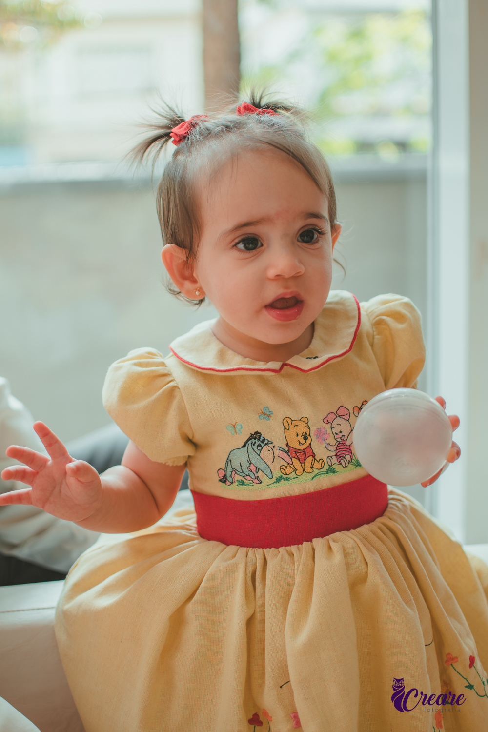Uma bebê brincando na piscina de bolinhas brancas, durante sua festa de aniversário de 1 ano.