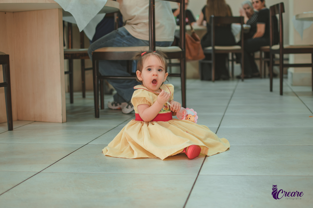 Uma bebê brincando no salão da sua festa de aniversário de 1 ano  feita em casa.