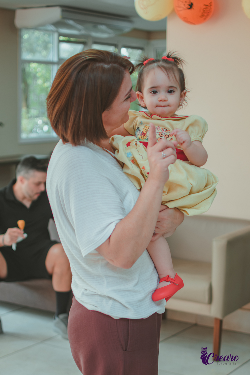 Uma bebê, brincando com uma mulher, no salão da sua festa de aniversário de 1 ano  feita em casa.