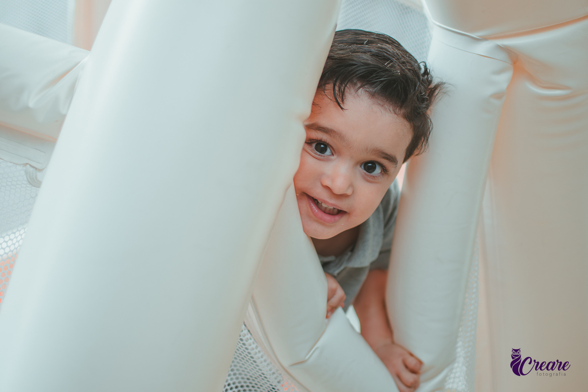 Um menino brincando no brinquado inflável, durante festa de aniversário infantil em casa.