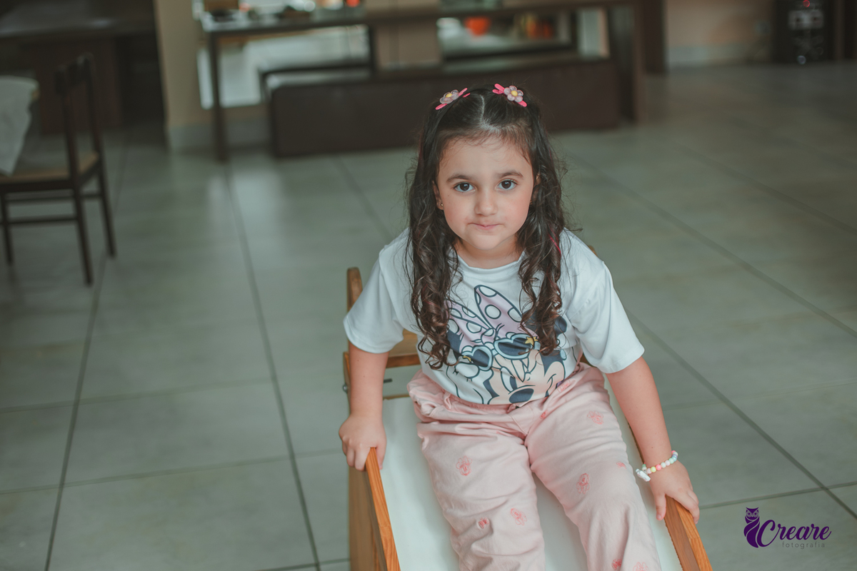 Uma menina, brincando no escorregador, durante festa de aniversário infantil em casa.