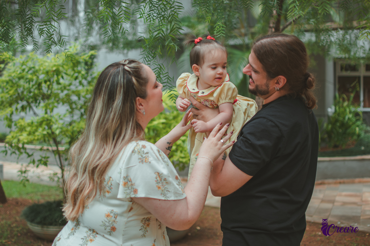 Um casa brincando com bebê de 1 ano, na area externa do prédio, durante sua festa de aniversário em casa.
