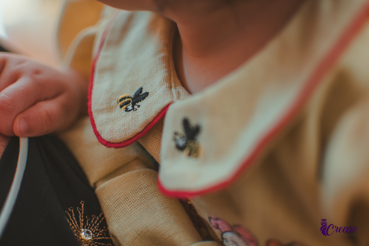 Detalhes da gola da roupa de uma bebê, bordada com abelhas.