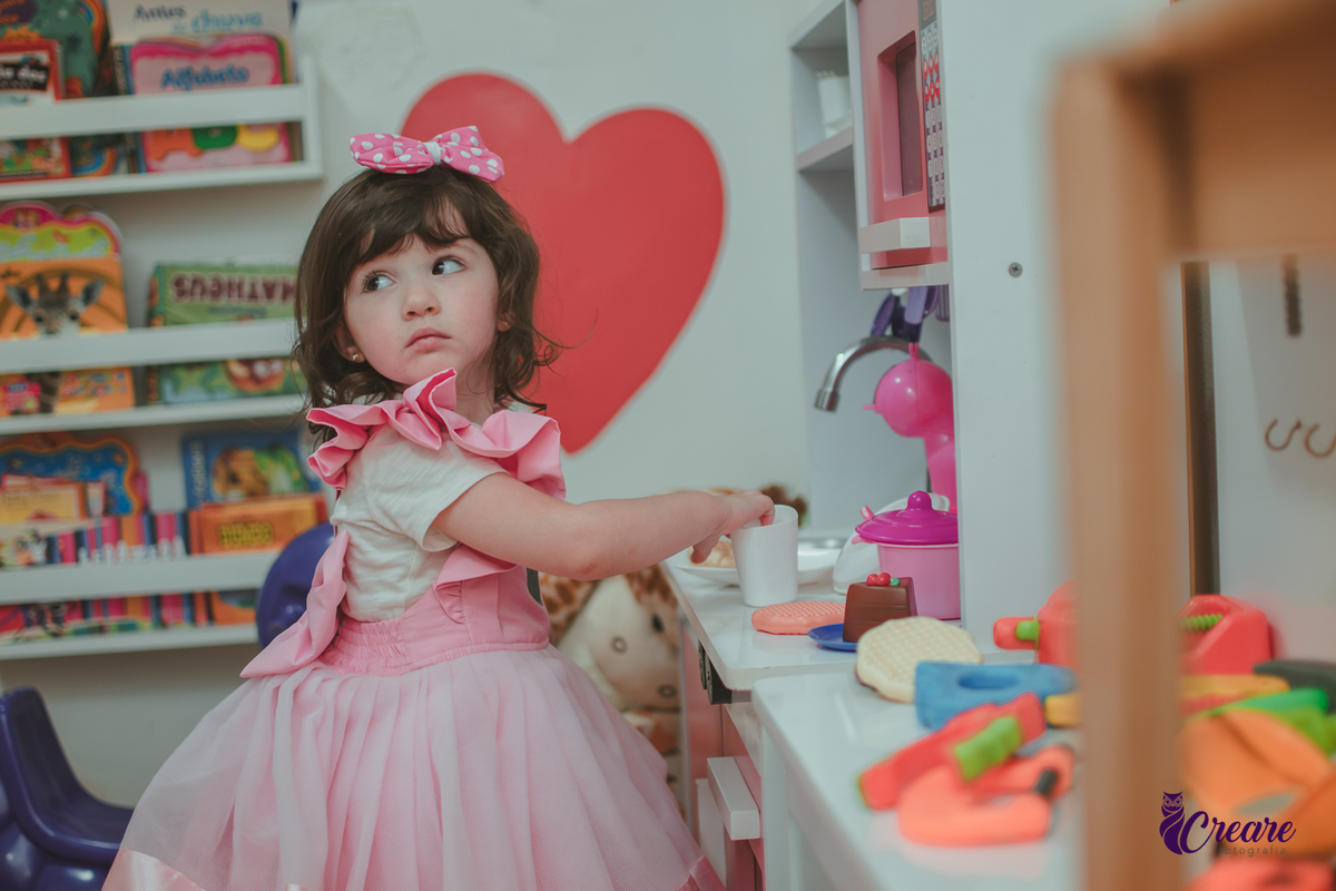 Uma menina brincando na cozinha de madeira durante sua festa de aniversário de 2 anos em São Caetano do Sul.
