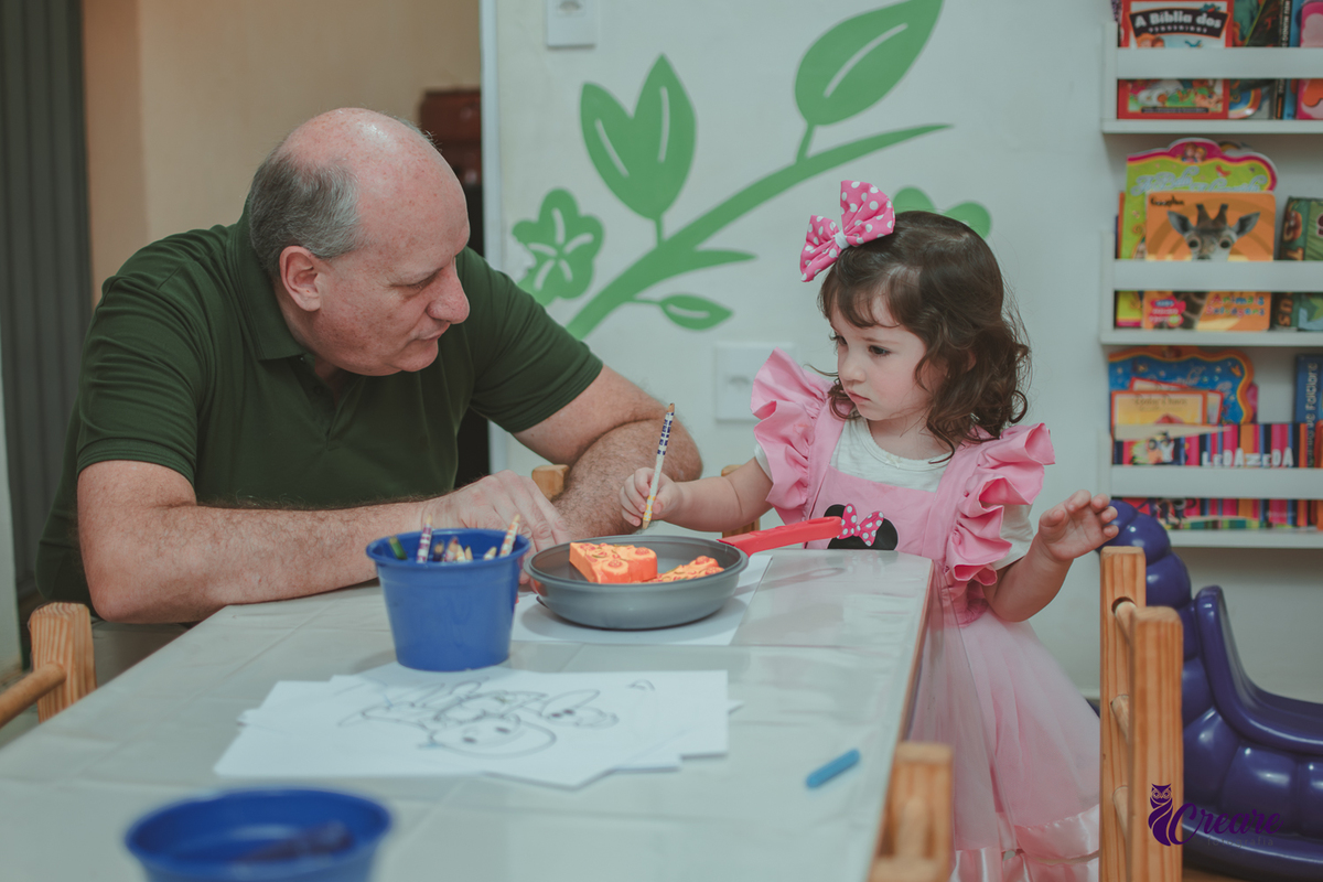 Uma menina brincando com seu avô na cozinha de madeira durante sua festa de aniversário de 2 anos em São Caetano do Sul.