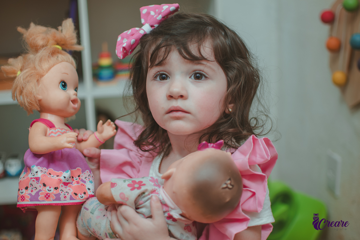 Uma menina brincando com bonecas durante sua festa de aniversário de 2 anos em São Caetano do Sul.