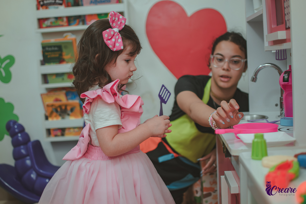 Uma menina brincando na cozinha de madeira durante sua festa de aniversário de 2 anos em São Caetano do Sul.