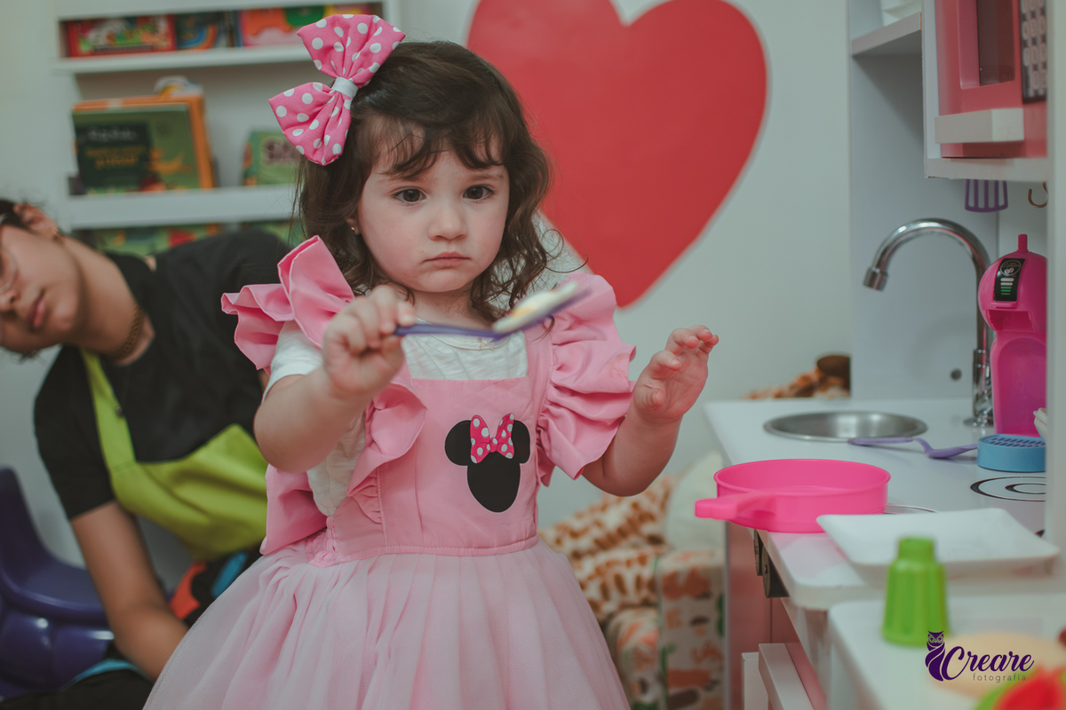 Uma menina brincando na cozinha de madeira durante sua festa de aniversário de 2 anos em São Caetano do Sul.