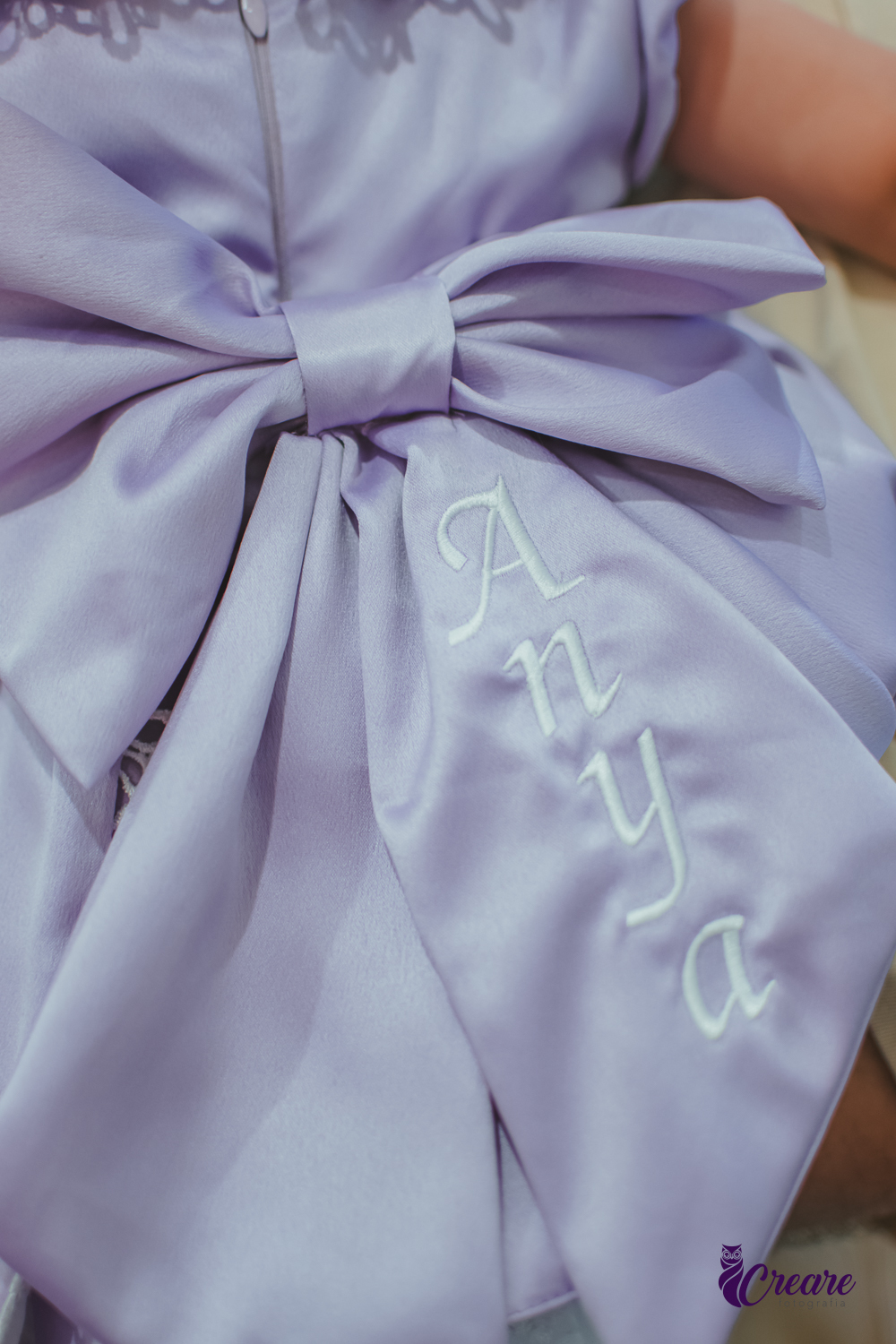 Detalhes do vestido roxo de uma bebê, escirto Anya.