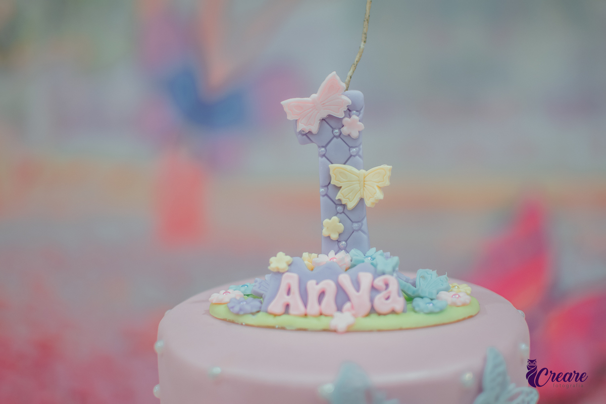 Uma vela de aniversário de 1 ano decorada com borboletas.