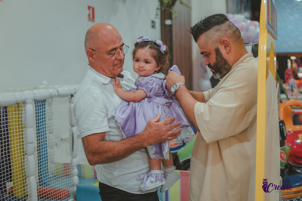 o Avó e pai de uma bebê arrumando o seu vestido, durante festa de aniversário.