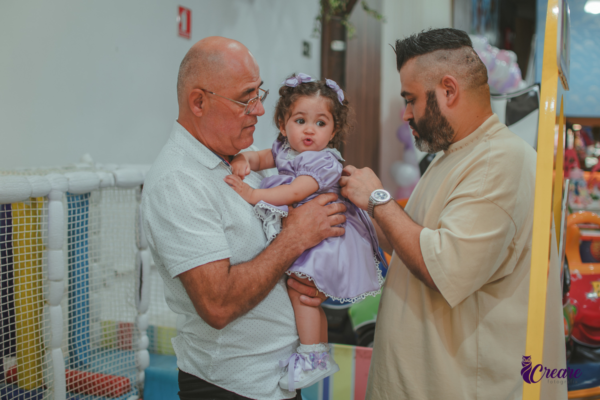 o Avó e pai de uma bebê arrumando o seu vestido, durante festa de aniversário.