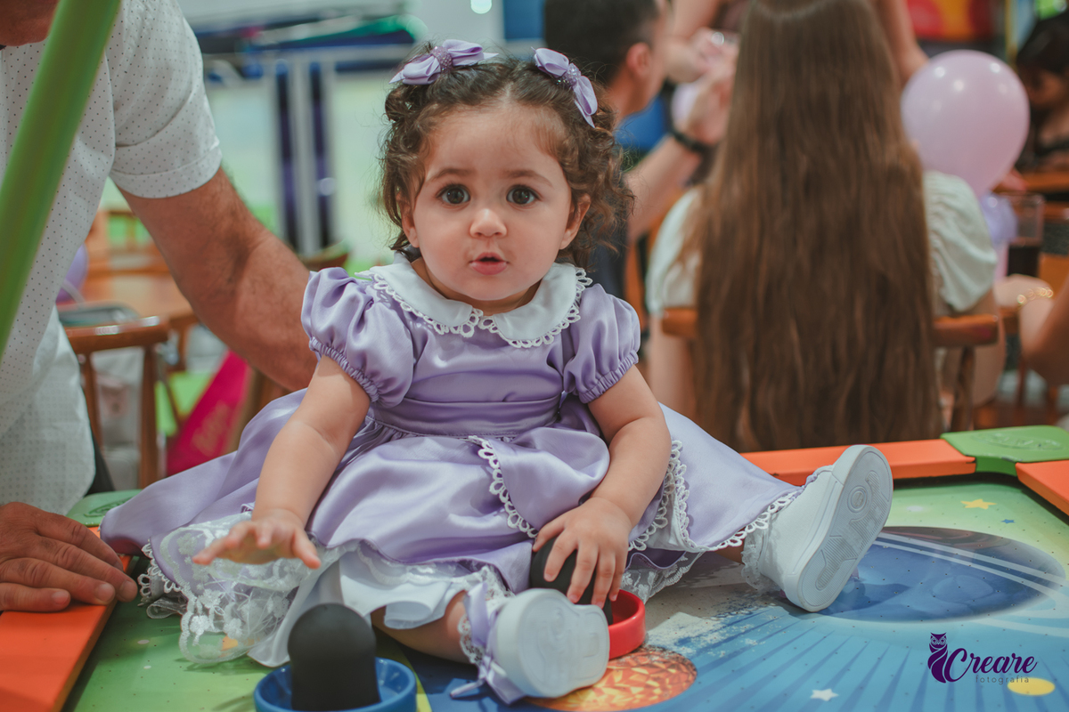 Uma bebê brincando durante sua festa de anievrsário de 1 ano.
