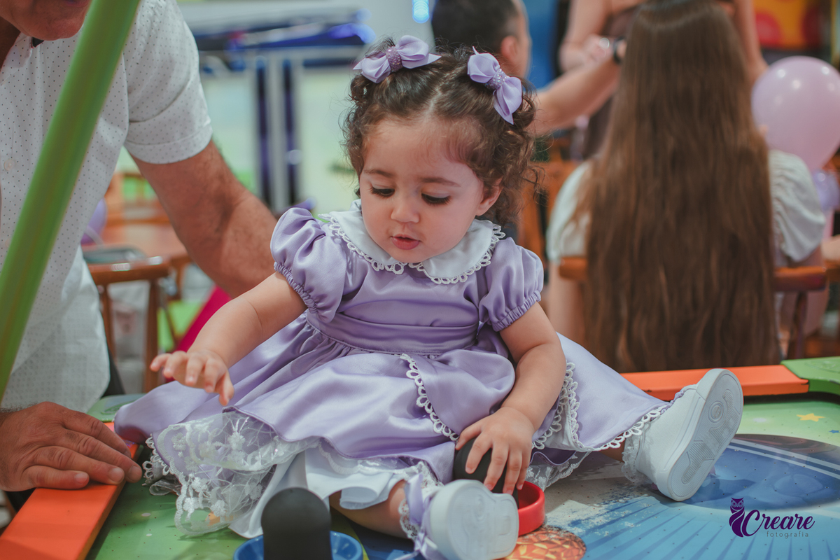Uma bebê brincando durante sua festa de anievrsário de 1 ano.