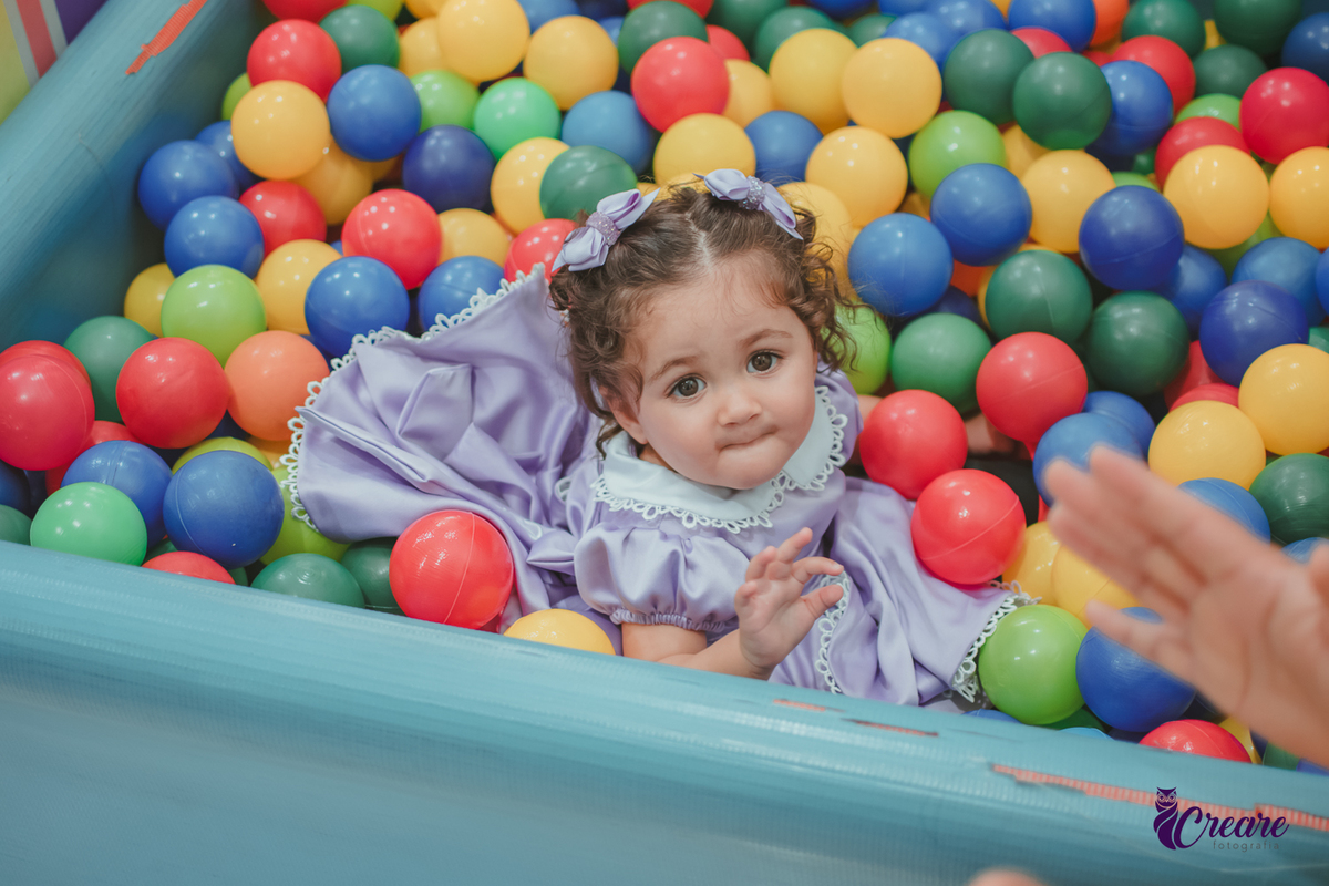 Uma bebê brincando na piscina de bolinhas, durante seu aniversário de 1 ano no Buffet É Pique em Mauá.