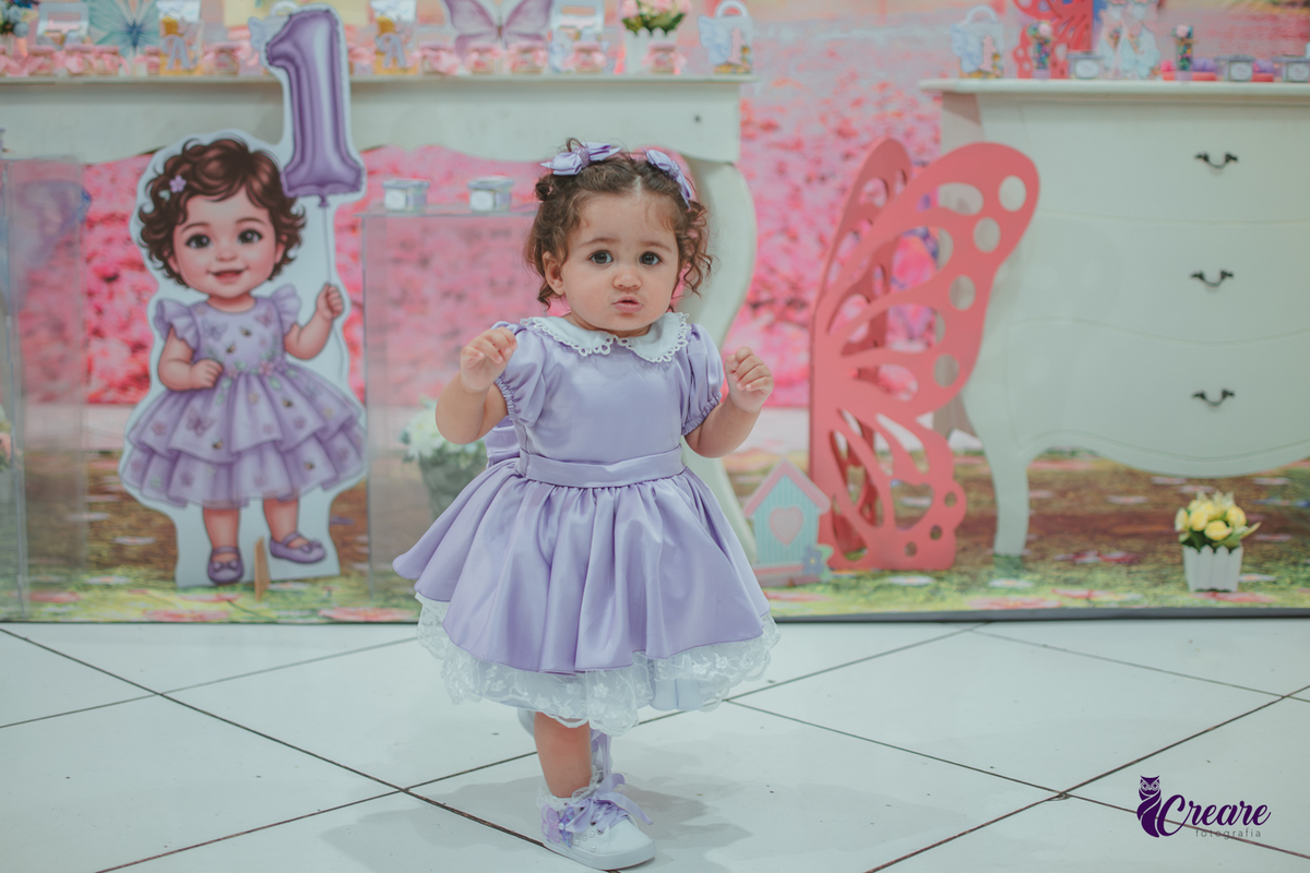 Uma menina usando vestido roxo e andando pelo salão, durante sua festa de aniversário de 1 ano no Buffet É Pique em Mauá.