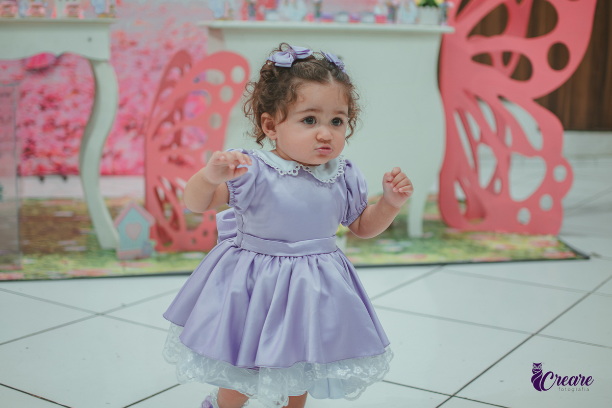 Uma menina usando vestido roxo e andando pelo salão, durante sua festa de aniversário de 1 ano no Buffet É Pique em Mauá.