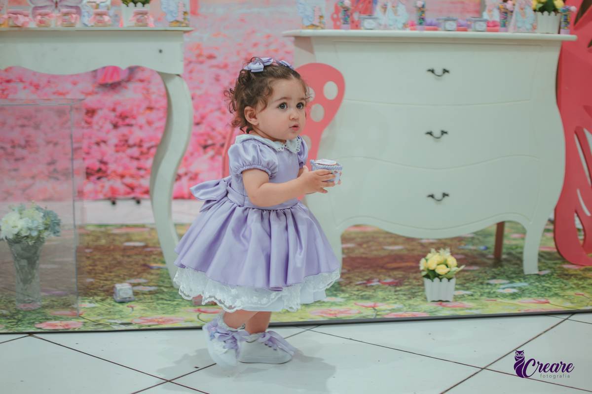 Uma menina usando vestido roxo e andando pelo salão, durante sua festa de aniversário de 1 ano no Buffet É Pique em Mauá.