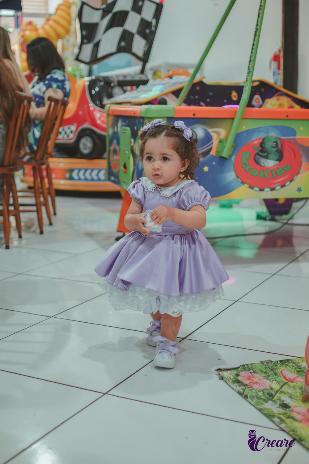 Uma menina usando vestido roxo e andando pelo salão, durante sua festa de aniversário de 1 ano no Buffet É Pique em Mauá.