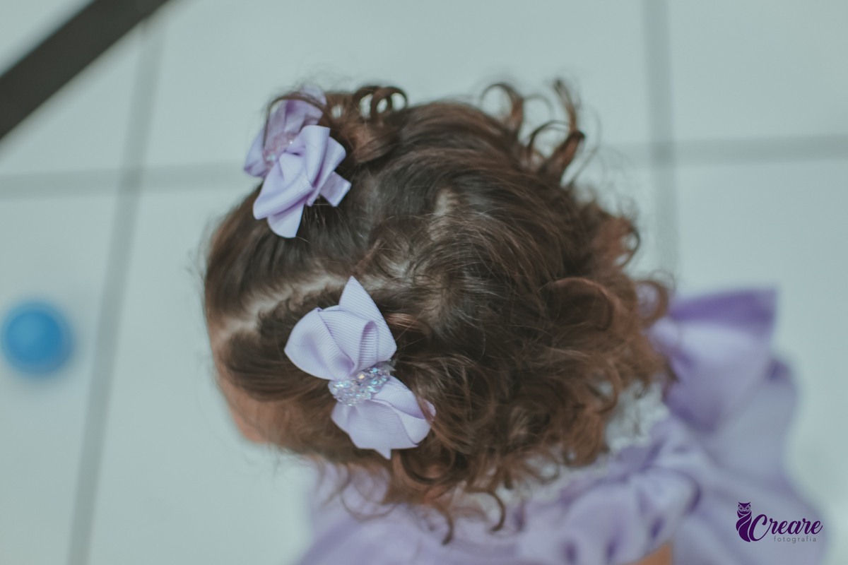 detalhes dos laços roxo no cabelo de uma bebê, durante festa de aniversário.
